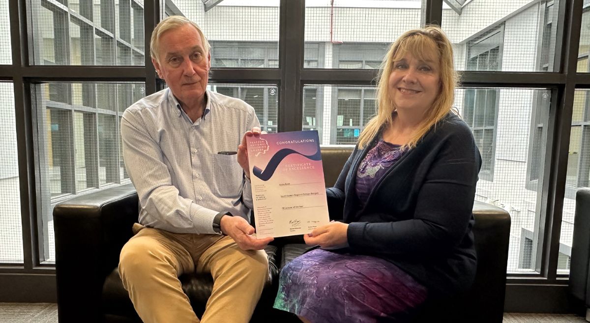 Picture of Ken Webb and Lizzie Buick sitting and presenting the Pearson Certificate of Excellence.